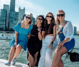 Fiends posing for a group photo on the bow of a yacht with the Chicago skyline in the background.
