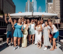 Friends posing on a boat rental in downtown Chicago with city buildings behind them.